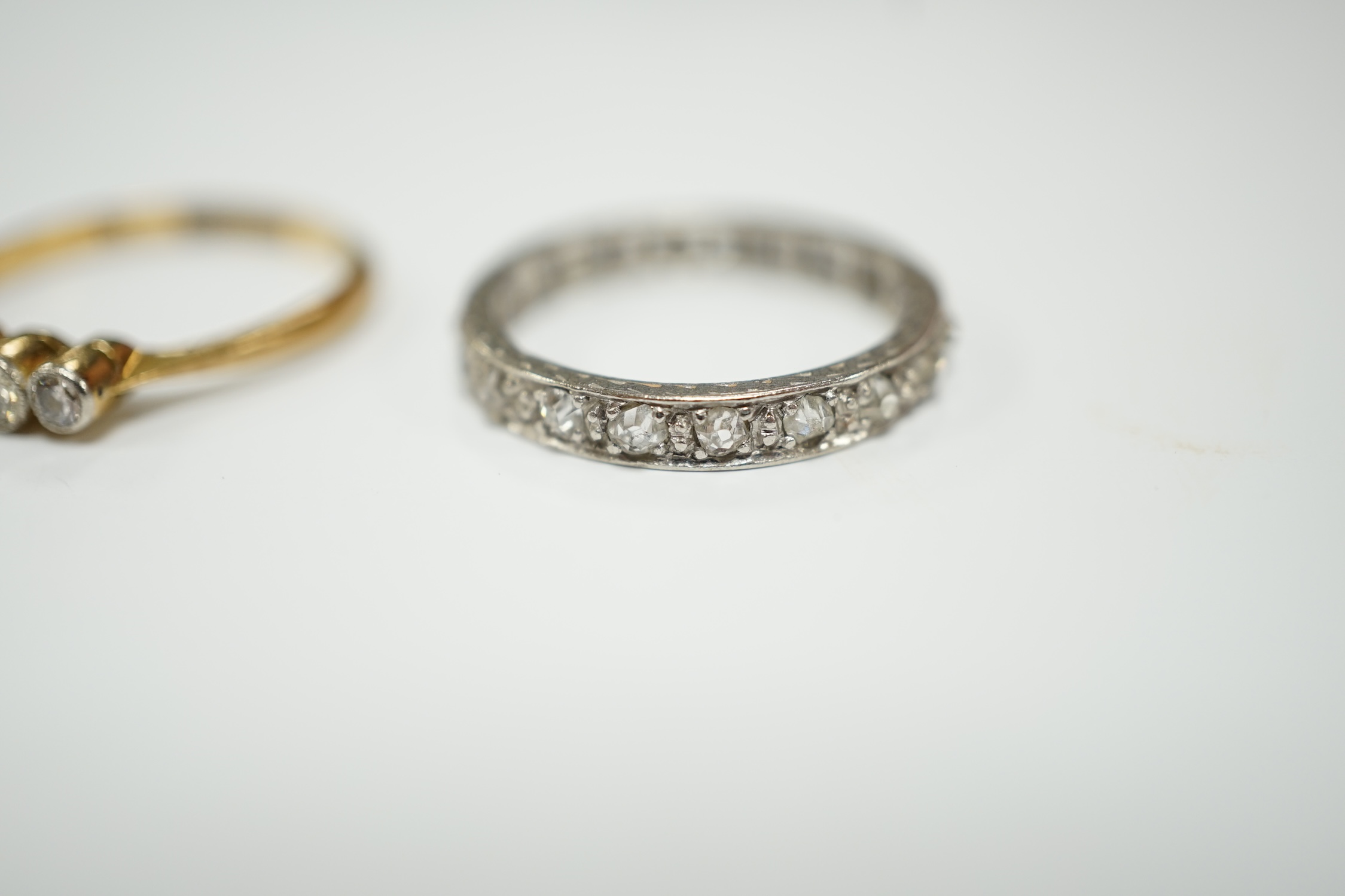 A white metal and diamond chip set full eternity ring, size L and an 18ct and graduated five stone diamond set ring, size M.